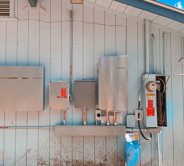 image of an Enphase battery being installed on the side of a house