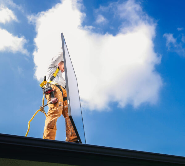 image of a Solar Maintenance Pros employee holding a solar panel on a roof top