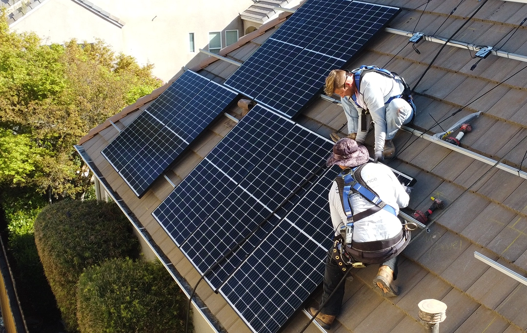 Two solar technicians working on solar panels on a rooftop
